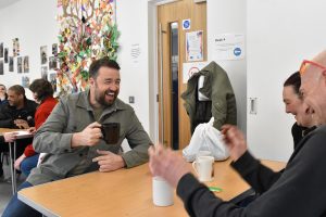 Jason Manford sharing a laugh with service users over a cup of tea in Petrus' Hub