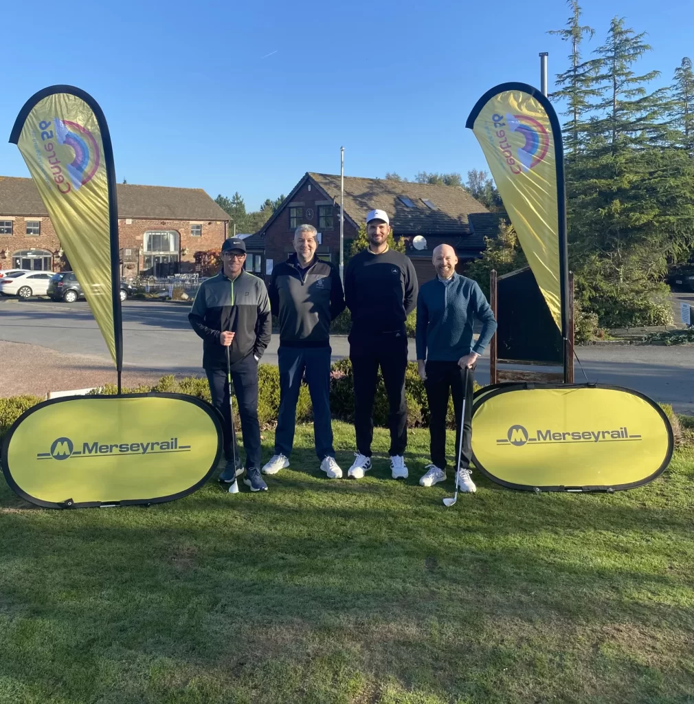 A group of golfers stand between branded flags