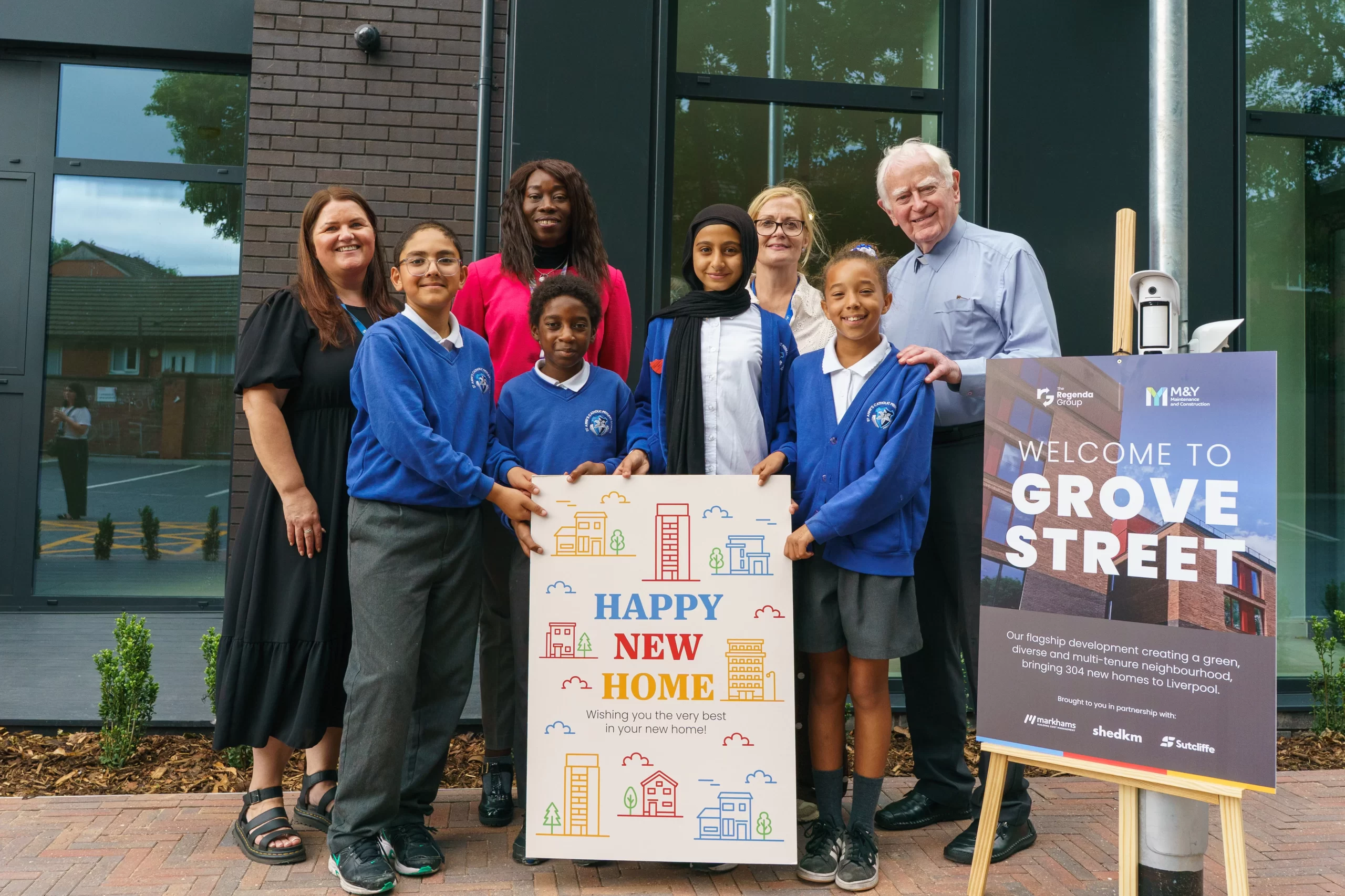 Children from St Anne's Primary School and Liverpool Civic Leaders outside Grove Street Development holding a happy new home card for residents.